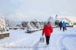Snow scene with people carrying shopping along 
urban street in winter. Benllech, Anglesey, Wales, UK, 
Britain.