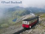 SNOWDON RAILWAY STEAM TRAIN approaching 
Summit Station with view west towards Nant-y-Betws 
through swirling cloud. Llanberris, Gwynedd, North 
Wales, UK, Europe

