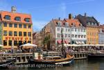 Old wooden boats moored on canal by pedestrianised 
waterfront street with outdoor cafes and colourful 
buildings in Nyhavn, Copenhagen, Zealand, Denmark, 
Europe