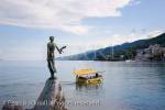 Maiden with the seagull statue by Zvonko Car (1956) 
on rocky promontory overlooking sea with tourist boat 
in seaside resort town on Kvarner Gulf coast in 
Adriatic. Opatija Istria Croatia Europe