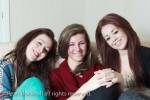 Three teenage friends aged 15 years sitting on a sofa 
together and smiling. UK Britain Europe. MR 