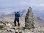 Walker by stone marker at top of Watkin path on 
Mount Snowdon with view to Y Lliwedd in Snowdon 
horseshoe in mountains of Snowdonia National Park, 
North Wales, UK, Britain