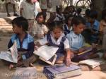 Junior school children sat on ground with books in 
shade of tree outside rural village school for outdoor 
lesson. Sania Madhya Pradesh India Asia