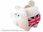 Piggy bank with British Union Jack and two sterling 
pound coins in the slot isolated on a white 
background. UK, Britain, Europe