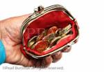 Senior pensioner holding a red purse open with 
money sterling coins in on a white background. 
England, UK, Britain, Europe