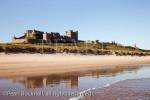 Bamburgh Castle reflected in wet sand on empty beach 
foreshore. Bamburgh, Northumberland, England, UK, 
Britain