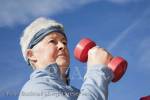 Senior woman exercising with dumbbell hand weights 
outdoors. Britain UK Europe. 

pensioner elderly person fitness health