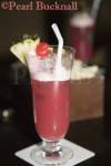 Singapore Sling cocktail with straw and cherry in glass 
on table in Raffles Hotel Long Bar at night. Singapore

