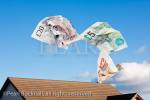 Composite image of Sterling money escaping from 
a house roof and floating away into blue sky to 
illustrate home heating costs concept. UK, Britain, 
Europe