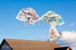 Composite image of Sterling money escaping from 
a house roof and floating away into blue sky to 
illustrate home heating costs concept. UK, Britain, 
Europe