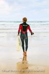 Perranporth, Cornwall, England, UK, Britain, Europe. 
One man wearing a wetsuit walking across the beach 
to the sea carrying a surf board