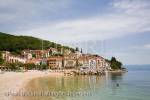 View along quiet beach to harbour and old town 
buildings on hillside in tourist resort on Kvarner coast 
of Istrian peninsula. Moscenicka Draga Istria Croatia 
Europe