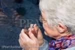Senior woman holding a warm drink looking out of the 
window on a cold dark night with snow outside in 
winter. MR 10/47