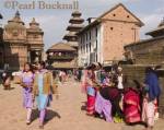 BUSY STREET near Taumadi Square bustling with 
colourfully dressed local people.  Pagodas of Cafe 
Nyatapola and Nyatapole Temple beyond.  Bhaktapur 
Kathmandu Valley Nepal Asia 

