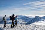 Three hikers on Pen Yr Ole Wen mountain summit with 
view to Mount Tryfan above low cloud in winter in 
mountains of Snowdonia National Park, North Wales, 
UK, Britain