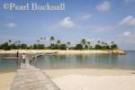 Tropical Siloso beach calm blue sea lagoon and 
wooden bridge linking small island Sentosa Island 
Singapore Asia