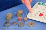 Person with a pile of British sterling coins using a 
calculator to count money. UK Britain MR 11/09